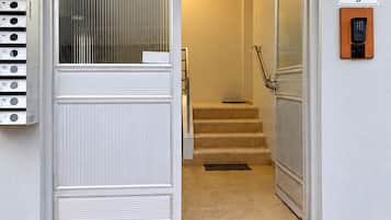 Una entrada de edificio con el número '43' sobre la puerta, un teclado de seguridad y una escalera que conduce al interior.