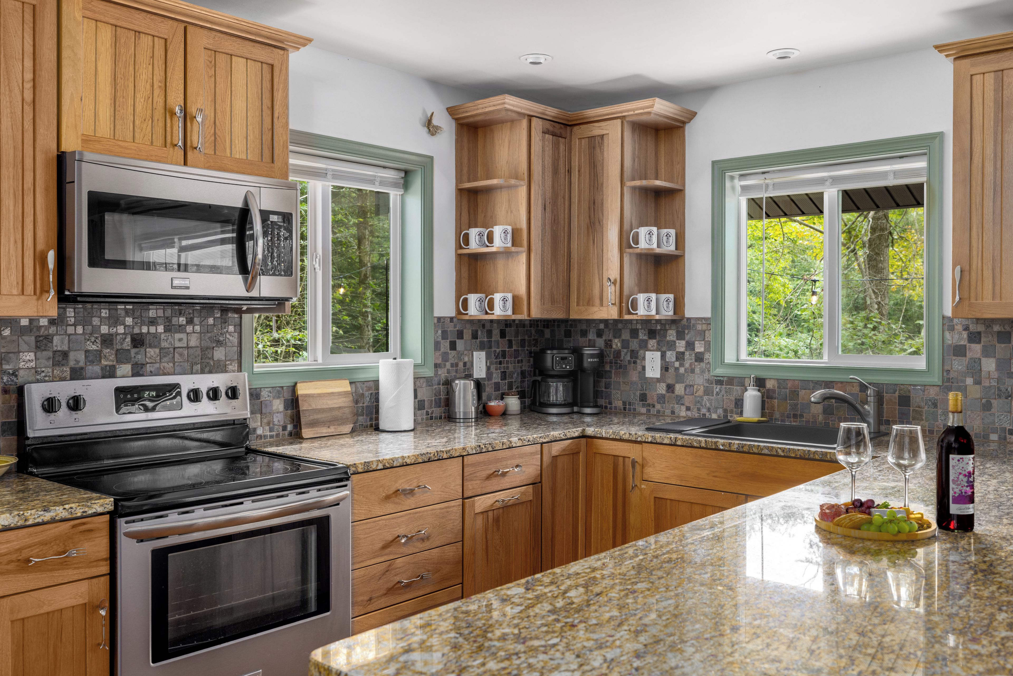 A kitchen with wooden cabinets, a stainless steel microwave, a coffee maker, and a wine bottle on the counter.