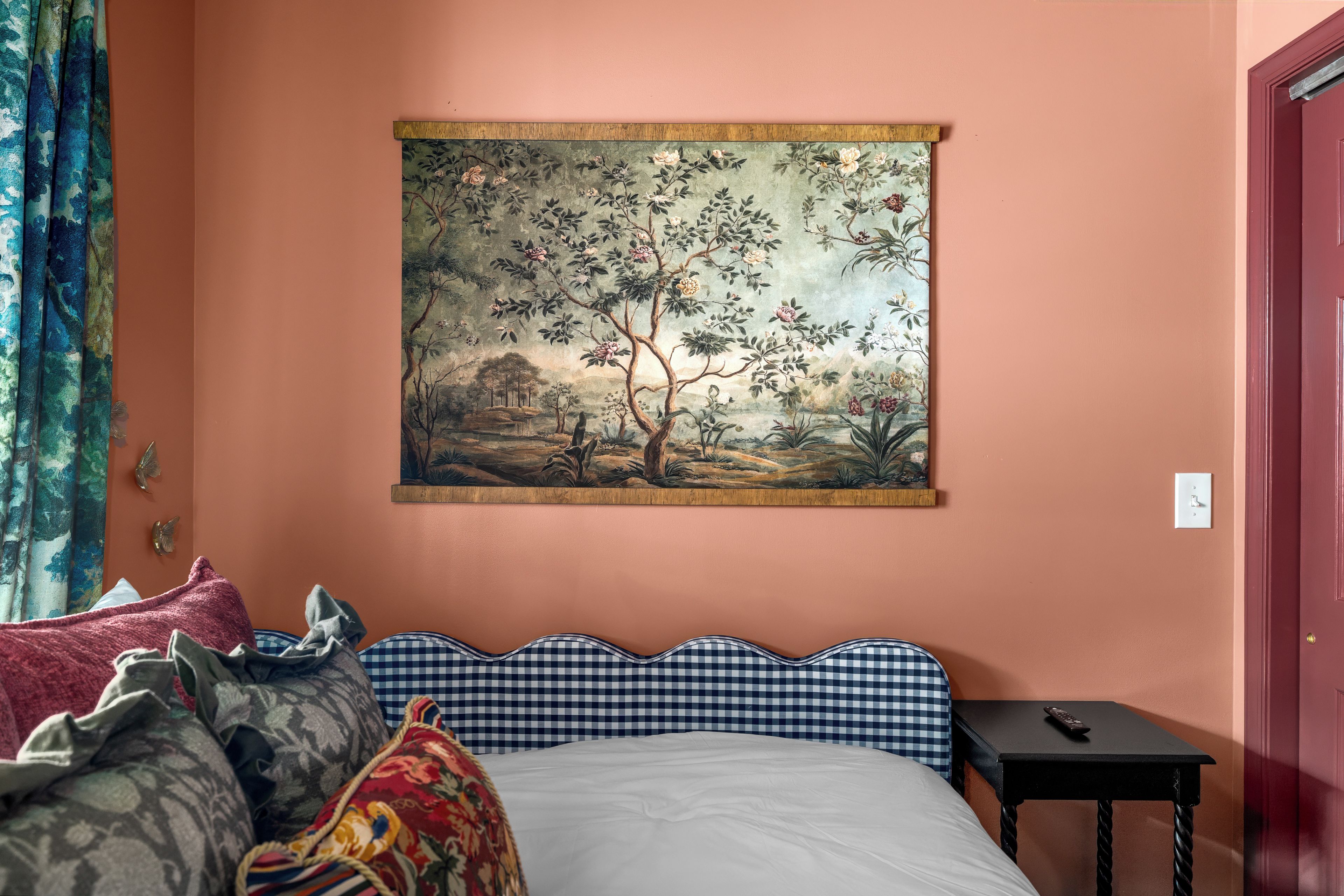 A bedroom with a bed, a painting, a nightstand, and a door.