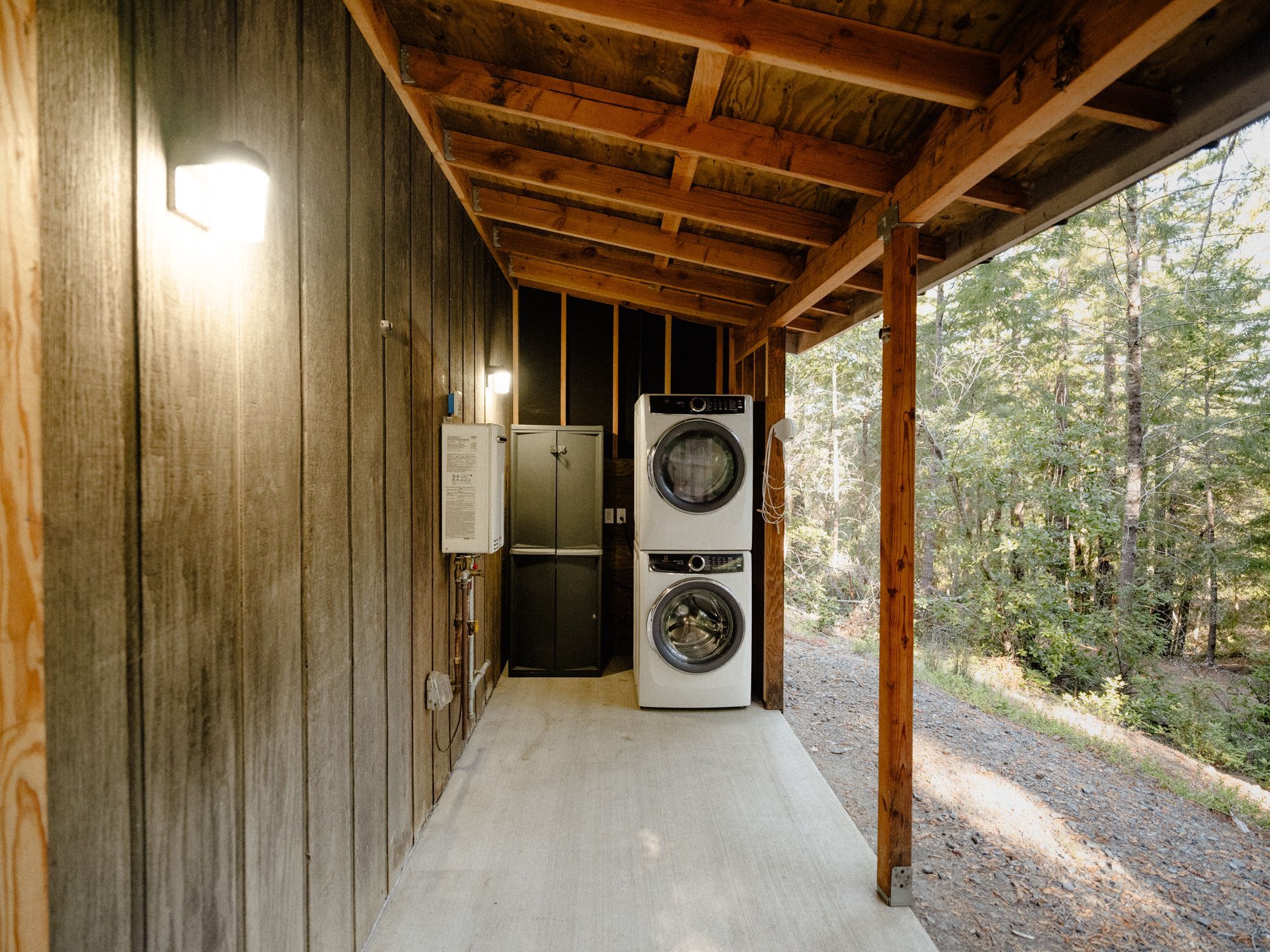 A wooden cabin with a concrete floor, a washing machine, and a small refrigerator.