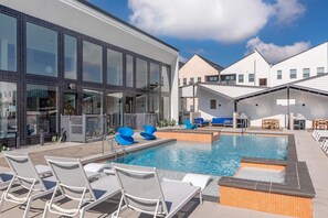 Ein Pool auf dem Dach mit Liegestühlen, eine kleine Whirlpool und eine überdachte Sitzecke.