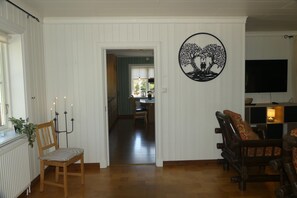 Un salon doté d’un plancher en bois, un coin repas avec une table et des chaises, un téléviseur fixé au mur et un élément décoratif mural.