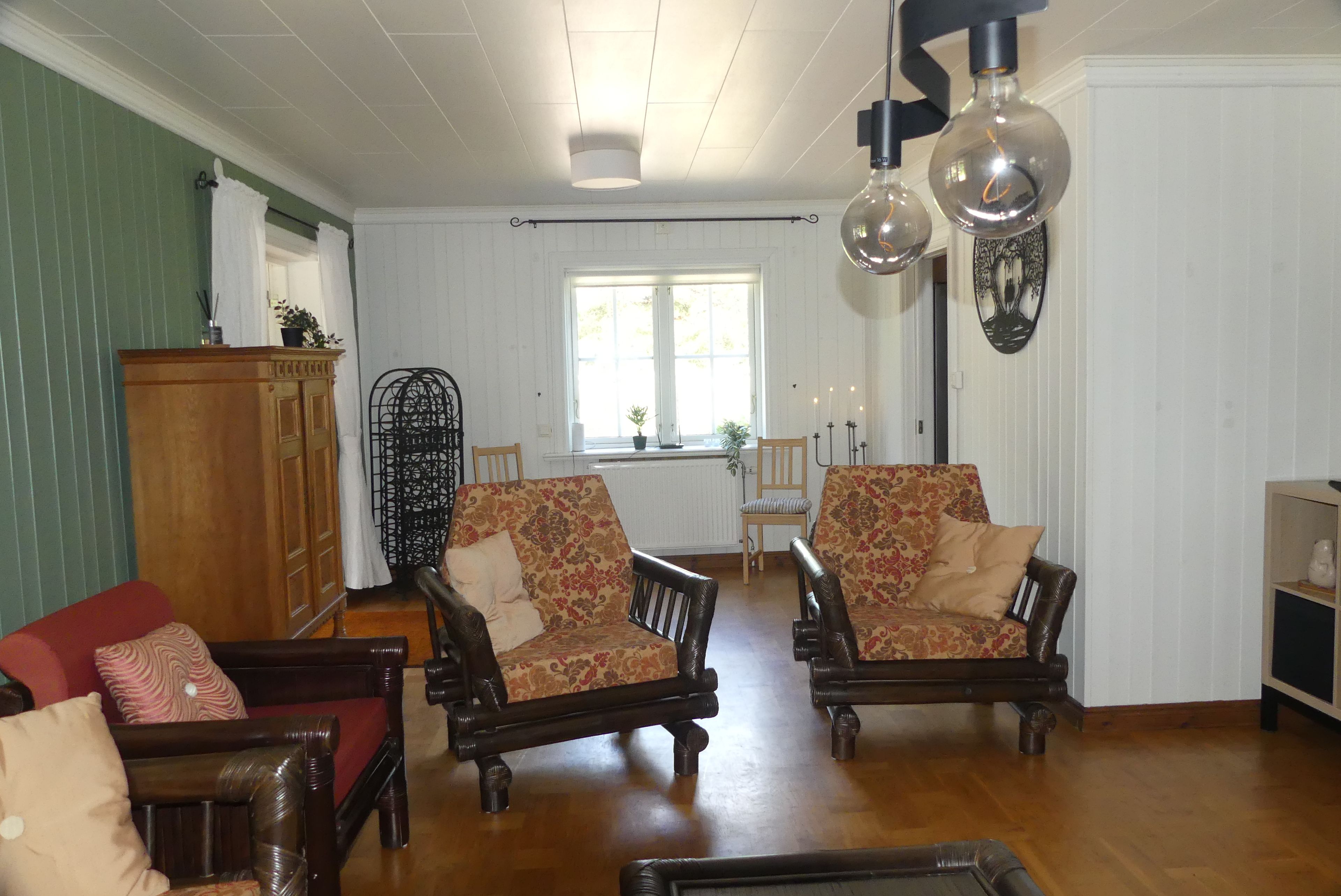 Uma sala de estar ampla com piso de madeira, uma janela grande e uma área de jantar com mesa e cadeiras.