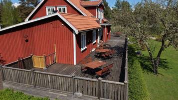 En röd lada med en träveranda och ett utomhusområde med sittplatser.