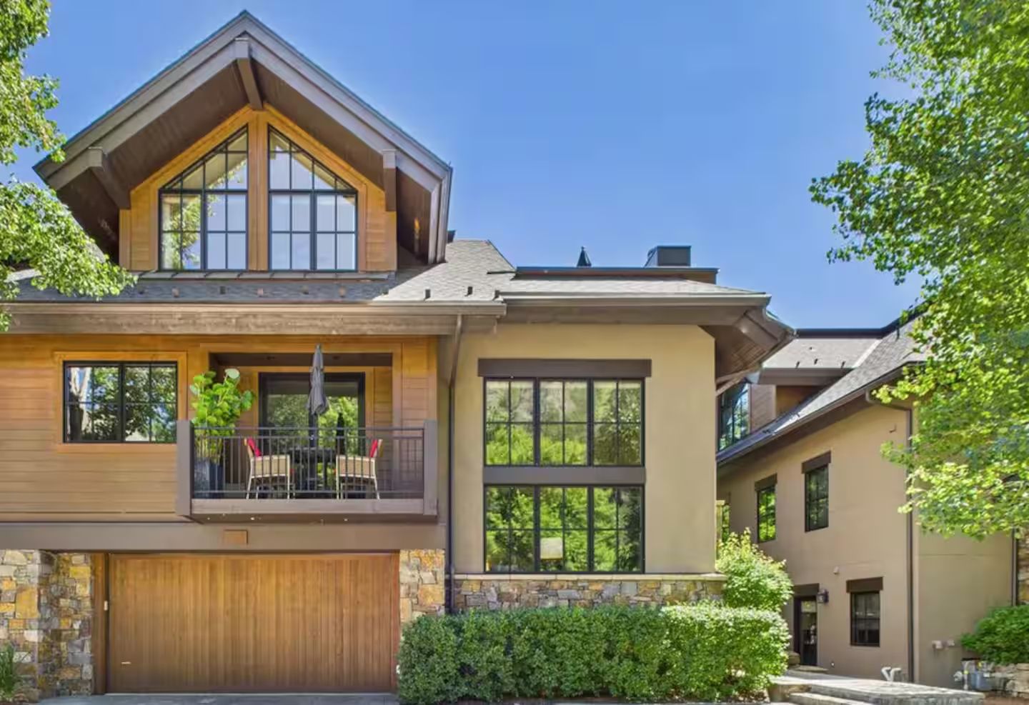A two-story house with a balcony, a garage, and a stone facade.