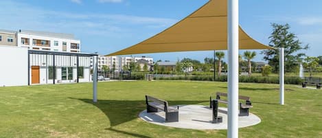 Un espace extérieur aménagé avec un auvent, des bancs et un bâtiment en arrière-plan.