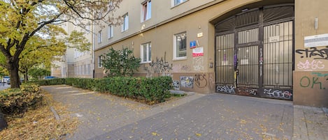 Un edificio con varias ventanas, una entrada protegida por una reja y grafitis en las paredes.