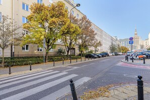 Eine Straße mit Zebrastreifen, parkenden Autos und einem Gebäude mit einem Uhrturm im Hintergrund.