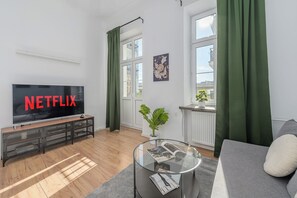 Ein modernes Wohnzimmer mit einem Flachbildfernseher, einem Glastisch und einem Sofa.