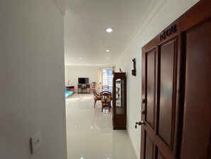 A hallway leading to a living area with a flat-screen TV, a sofa, and a dining table with chairs. - Spectacular apartment with an ocean view (Cartagena de Indias)