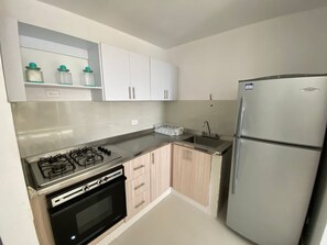A kitchen with a gas stove, oven, double sink, and a refrigerator. - Spectacular apartment with an ocean view (Cartagena de Indias)