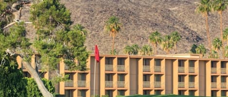 A hotel with a flat roof, multiple balconies, and a flagpole.