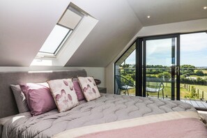 Ein Schlafzimmer mit einem großen Bett, einem Oberlicht und Blick auf einen Garten.