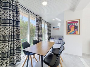 A dining area with a table and chairs, a covered seating area, and a poster on the wall. - SANTA CATALINA Rosas / Roses – INTERimmo (Rosas / Roses)