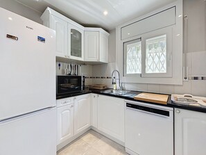 A modern kitchen with white cabinetry, a black countertop, and a built-in dishwasher. - SANTA CATALINA Rosas / Roses – INTERimmo (Rosas / Roses)