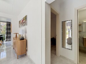 A hallway with a wooden console table, a mirror, and a door leading to another room. - SANTA CATALINA Rosas / Roses – INTERimmo (Rosas / Roses)