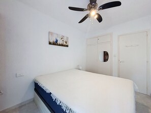A bedroom with a bed, a ceiling fan, a wardrobe, and a wall-mounted picture. - SANTA CATALINA Rosas / Roses – INTERimmo (Rosas / Roses)