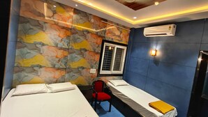 Habitación de hotel con dos camas, una silla roja, un ventanal y un equipo de aire acondicionado.
