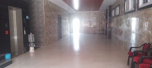 A hotel lobby with a marble floor, a reception desk, and red chairs. - Srivara Grand Mantralayam  (Mantralayam)