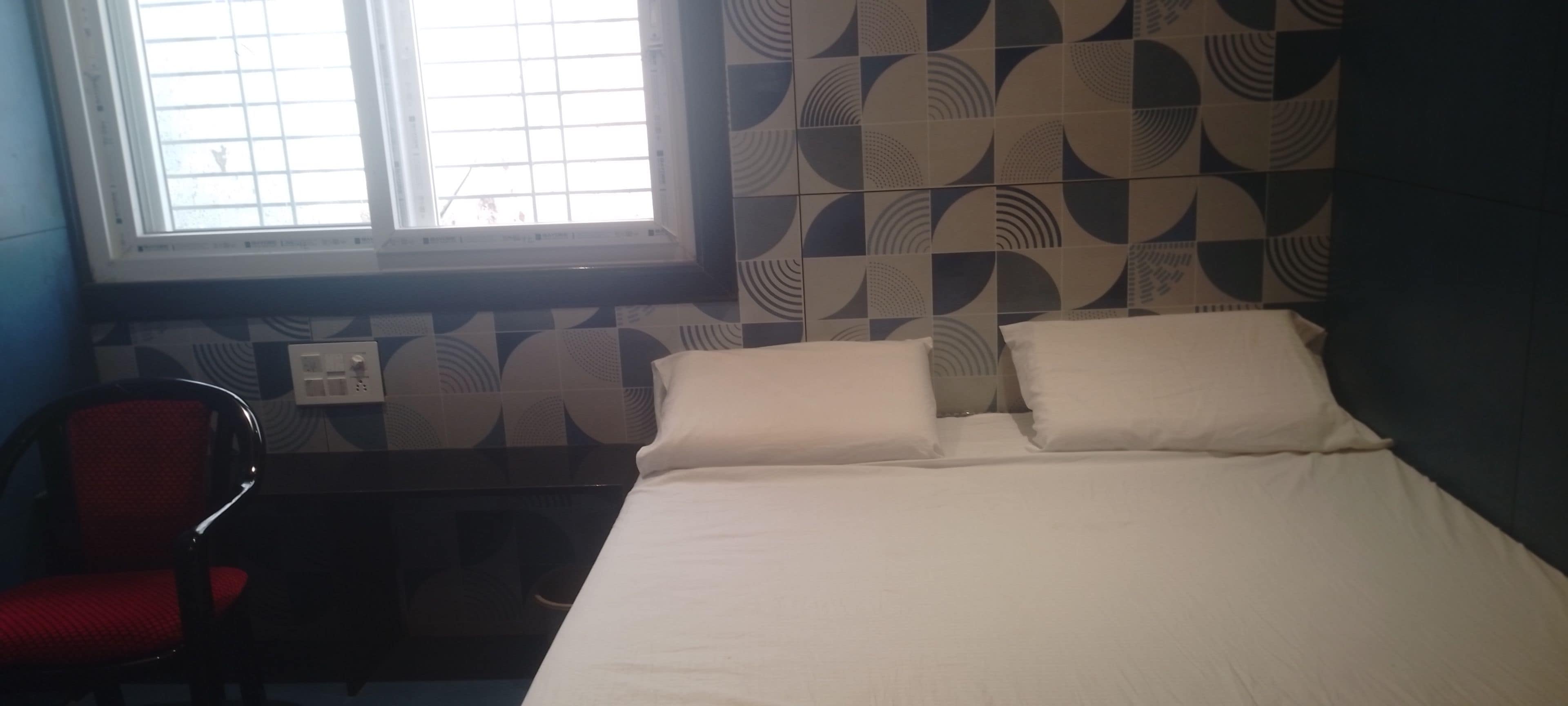 Una stanza con un letto, una finestra, una sedia e piastrelle murali decorate.