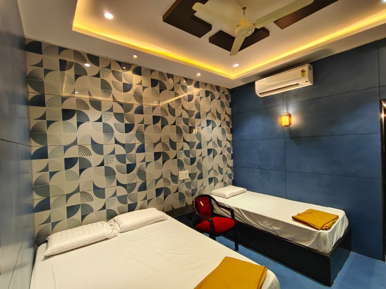 Habitación de hotel con dos camas, una silla roja y una pared con estampado.
