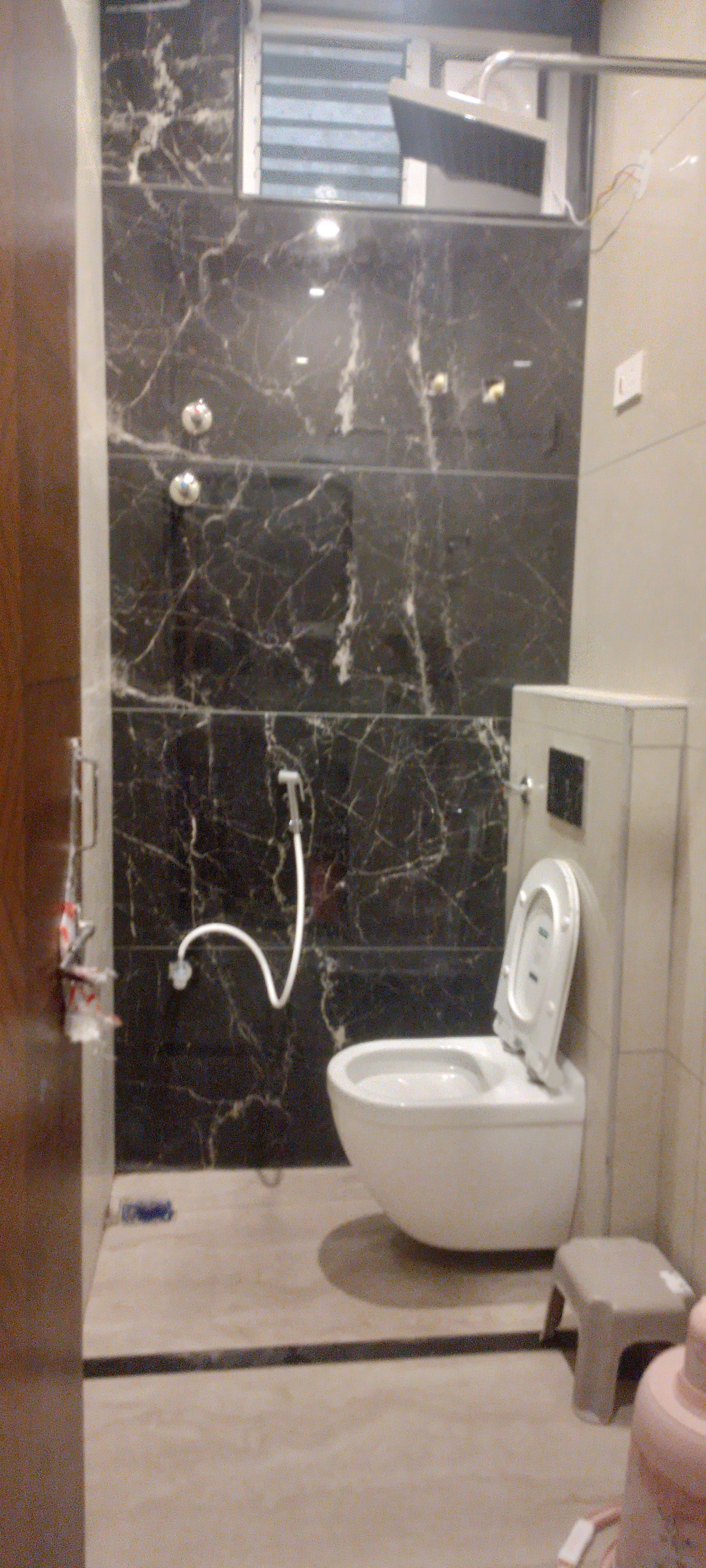 Un baño con inodoro, ducha y pared de mármol.