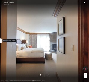 Quarto de hotel com uma cama grande, um painel lateral, área de estar e lareira.