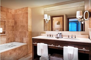 Un baño moderno con un espejo grande, dos lavamanos, una bañera y un perchero para toallas.
