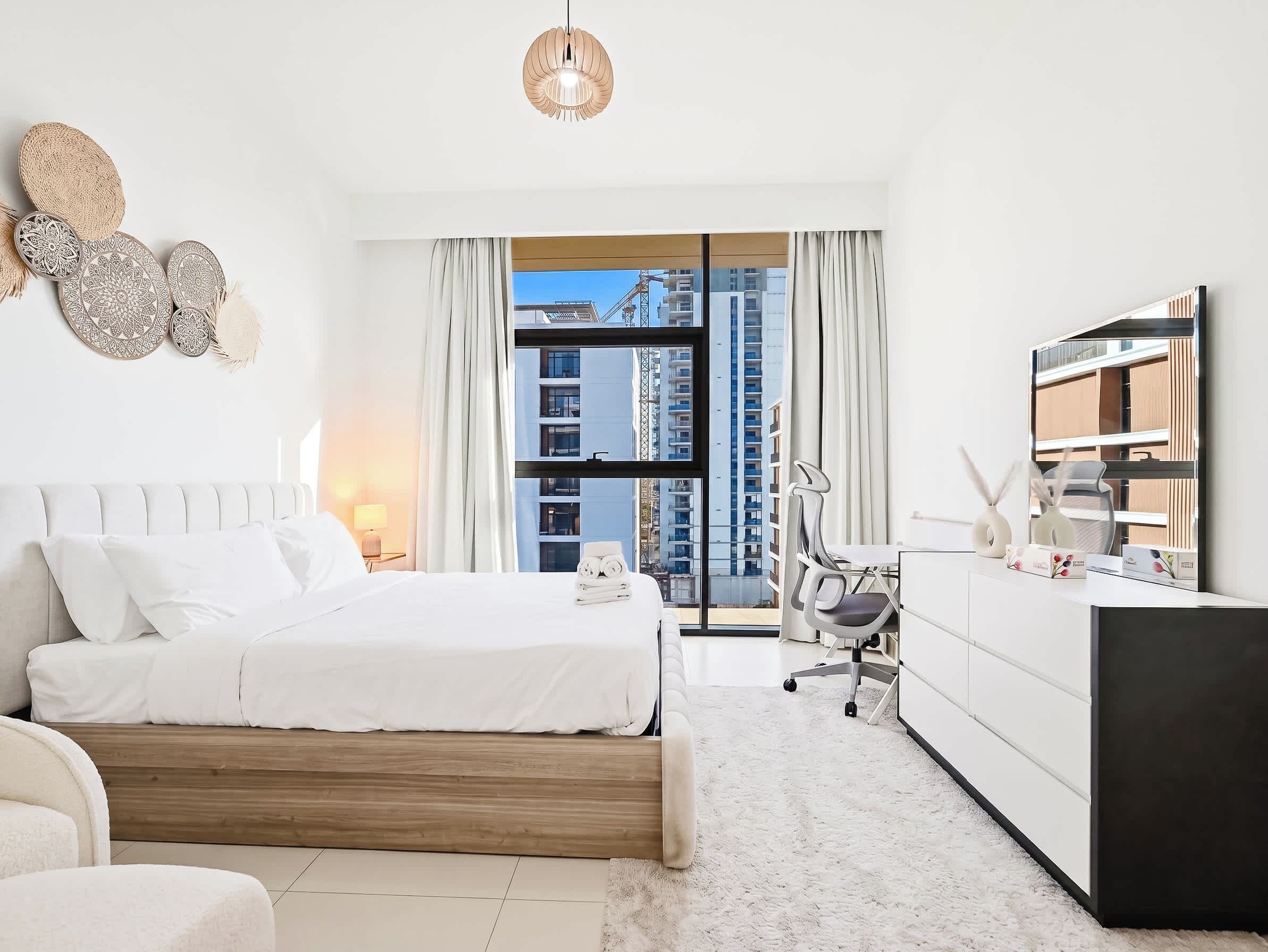 Ein modernes Hotelzimmer mit einem großen Bett, einem Schreibtisch und Blick auf eine Stadtlandschaft.