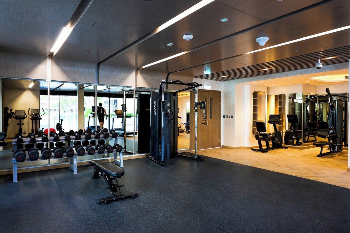 Ein Fitnessstudio mit Trainingsgeräten, Gewichtsständern und einer Spiegelwand.