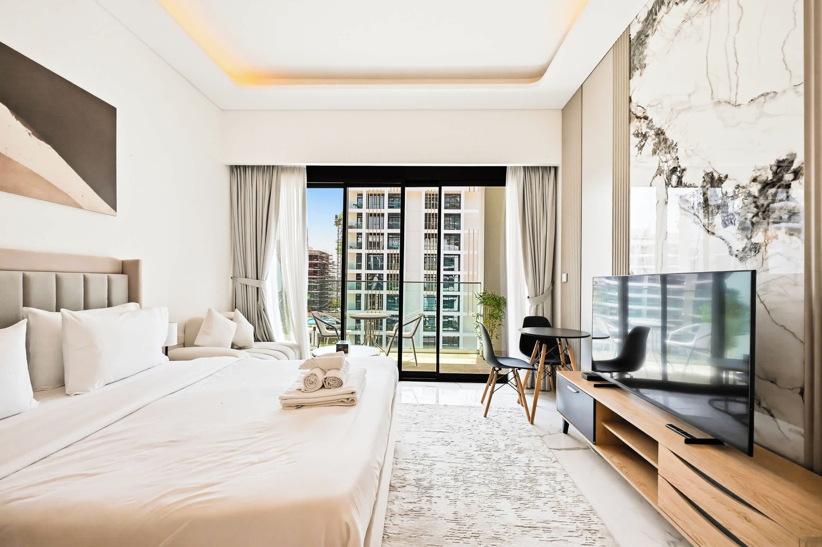 Quarto de hotel moderno com cama grande, televisão de tela plana e varanda com vista para a cidade.