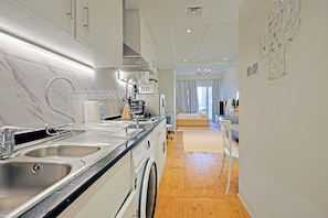 A modern kitchen with a double sink, stainless steel appliances, and a wooden floor. - JLT Studio · Lake View · Metro 5min (دبي)