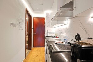A modern kitchen with a wooden door, stainless steel appliances, and a marble backsplash. - JLT Studio · Lake View · Metro 5min (دبي)
