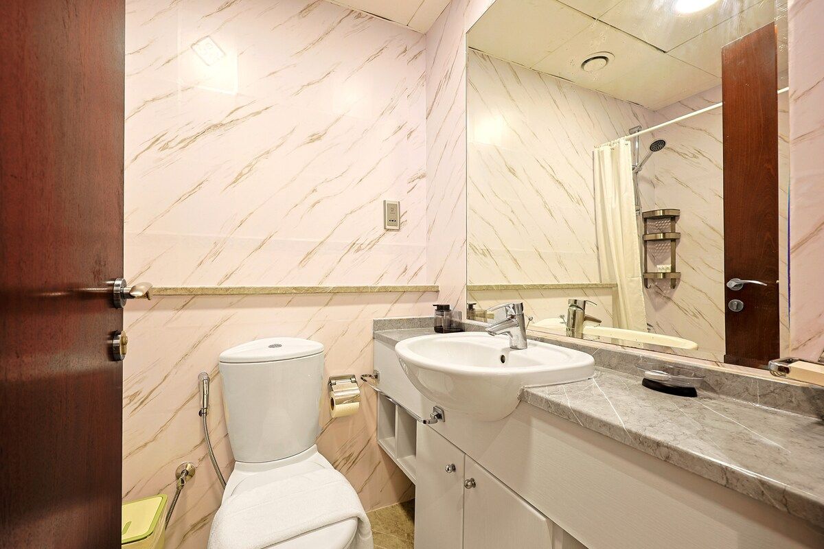 A bathroom with a toilet, sink, and mirror.