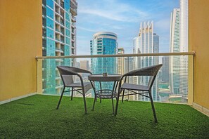 A balcony with artificial grass, two wicker chairs, and a small table. - JLT Studio · Lake View · Metro 5min (دبي)