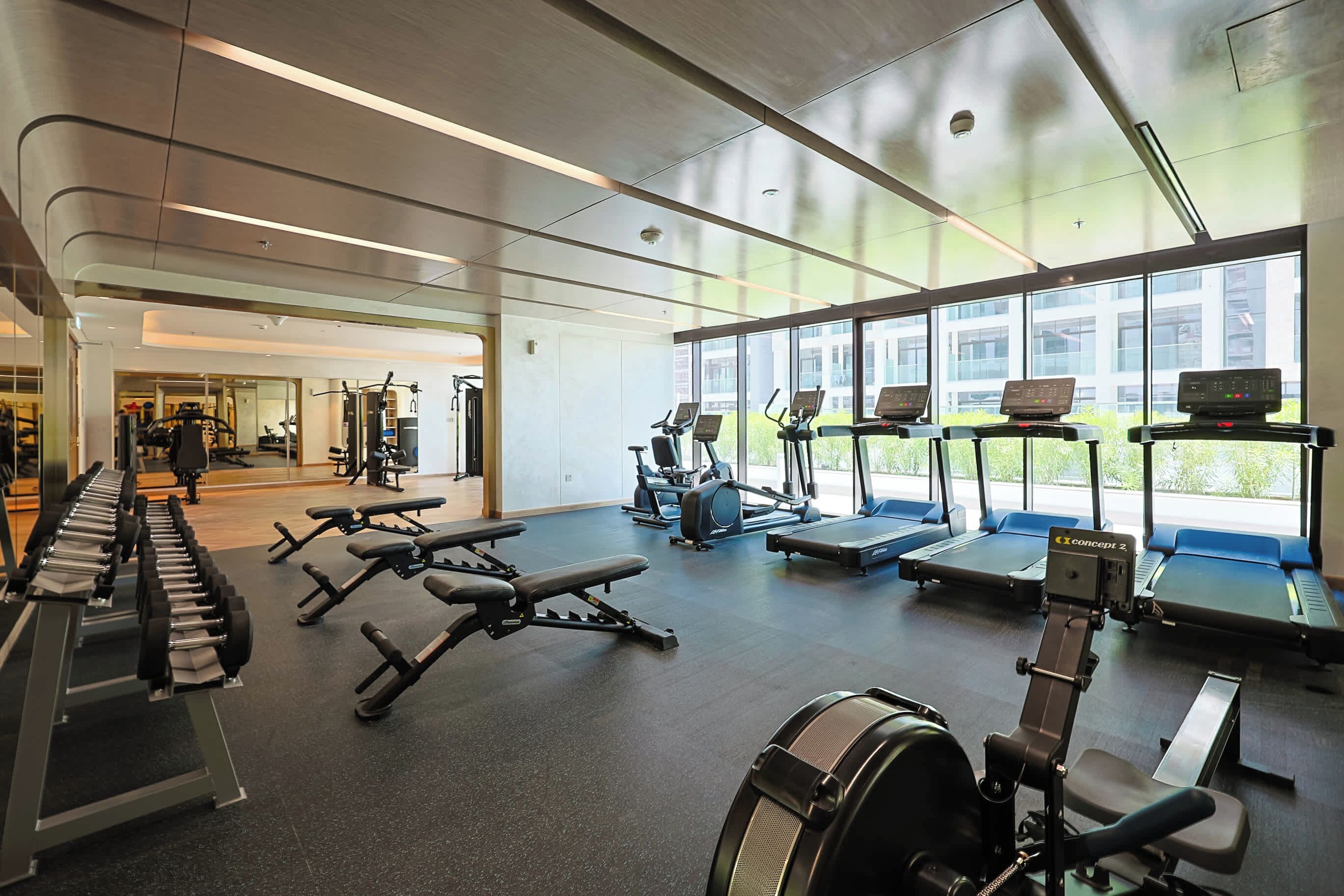 Ett gym med olika typer av träningsutrustning, stora fönster och en modern design.