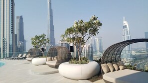 A rooftop terrace with modern seating, greenery, and a city skyline view. - Imperial 2BR · Burj View · Downtown (Dubai)