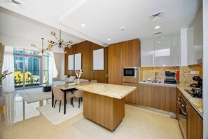A modern kitchen with a central island, wooden cabinetry, and a large window providing a view of the city. - Imperial 2BR · Burj View · Downtown (Dubai)