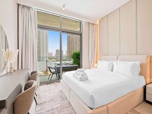 Ein Hotelzimmer mit einem großen Bett, einem Schreibtisch, einem Sessel und Blick auf die Stadt.