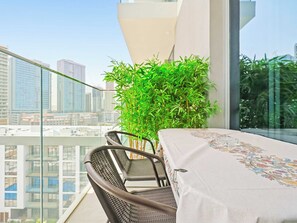 Ein Balkon mit Tisch und Stühlen, einem Blumentopf und Blick auf die Stadt.