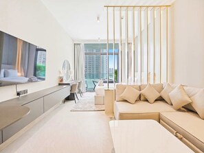 A modern living room with a sofa, a flat-screen TV, and a dining area with a table and chairs. - Modern Studio Escape - Relax & Unwind (Dubai)