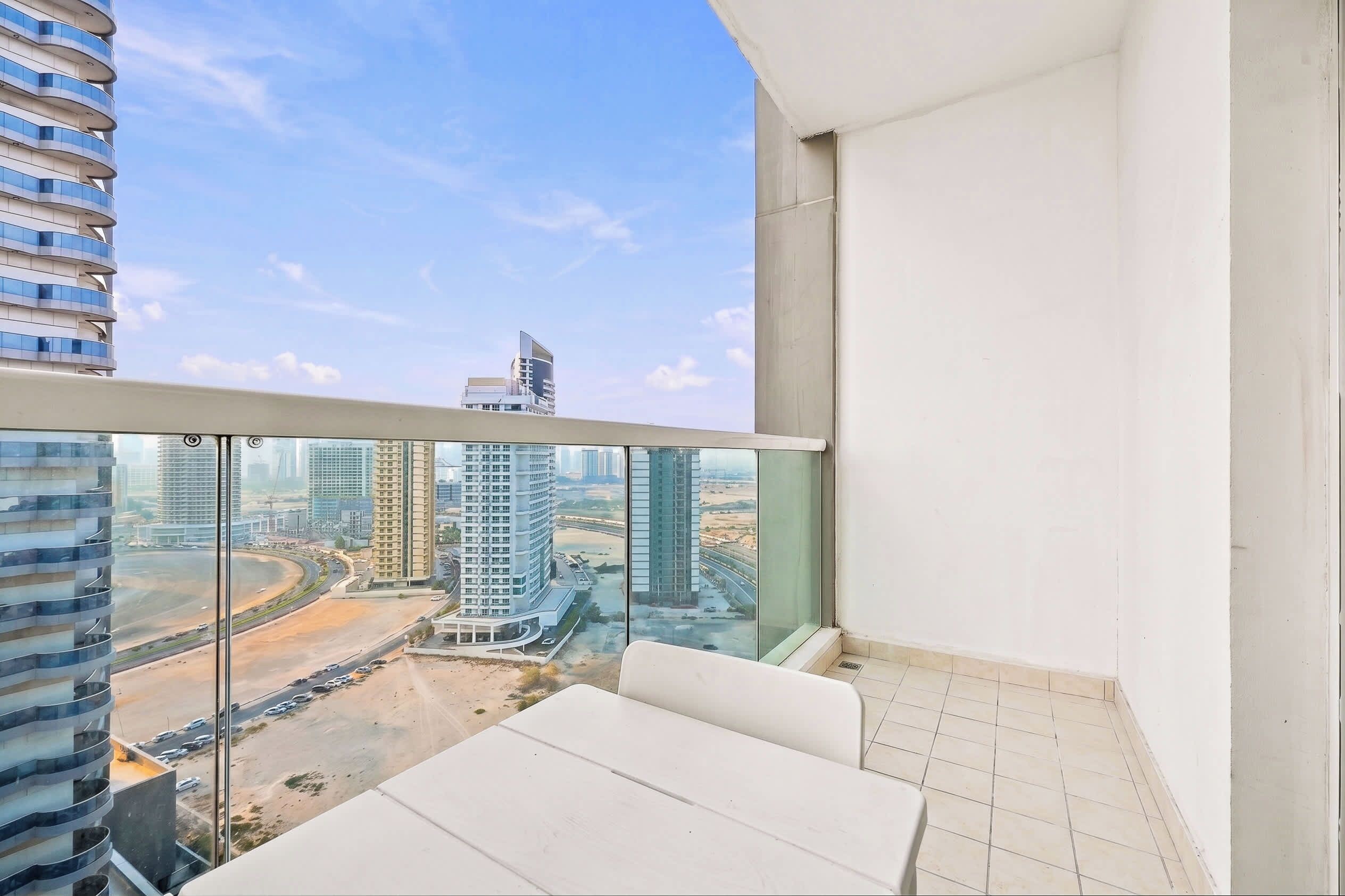 Un balcon offrant une vue sur le paysage urbain, avec notamment des immeubles de grande hauteur et une route.