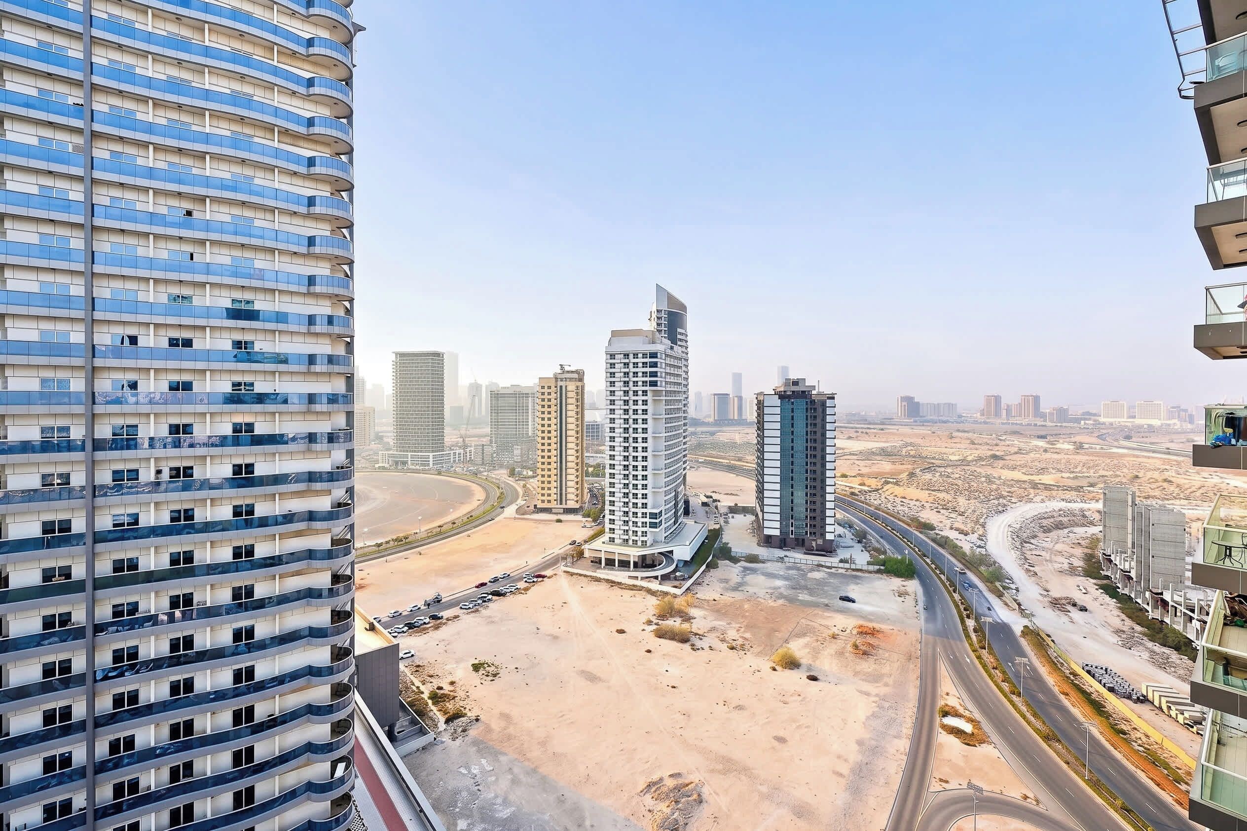 Un immeuble de grande hauteur doté de nombreux balcons et offrant une vue sur un paysage désertique, avec des routes et d’autres bâtiments.