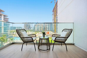 A balcony with two wicker chairs, a small round table, and a potted plant. - Celadon 2BR · City Walk · Pool & Gym (Dubai)