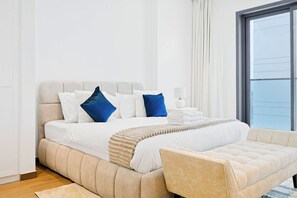 Une chambre moderne avec un grand lit, une table de chevet et une fenêtre avec des rideaux.