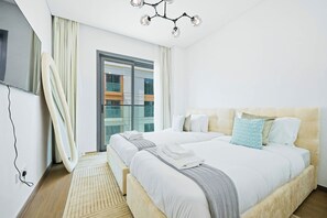 A modern hotel room with a large bed, a flat-screen TV, and a view of the city through the window. - Celadon 2BR · City Walk · Pool & Gym (Dubai)