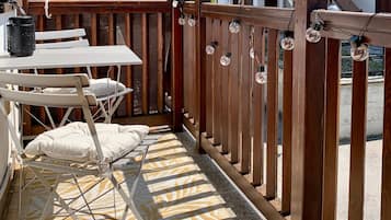 Ein Balkon mit Tisch und Stühlen, einem gemusterten Teppich und einem Holzzaun.