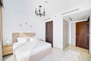 Ein modernes Schlafzimmer mit einem großen Bett, Nachttischen, einem Kronleuchter und einem Kleiderschrank.
