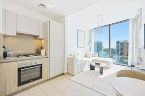 A modern apartment with a kitchen, living area, and large windows offering a city view. - Sobha Waves 1BR · Pool & Gym · MBR City (Dubai)
