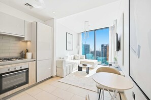 A modern kitchen with a gas stove, oven, and white cabinetry. - Sobha Waves 1BR · Pool & Gym · MBR City (Dubai)
